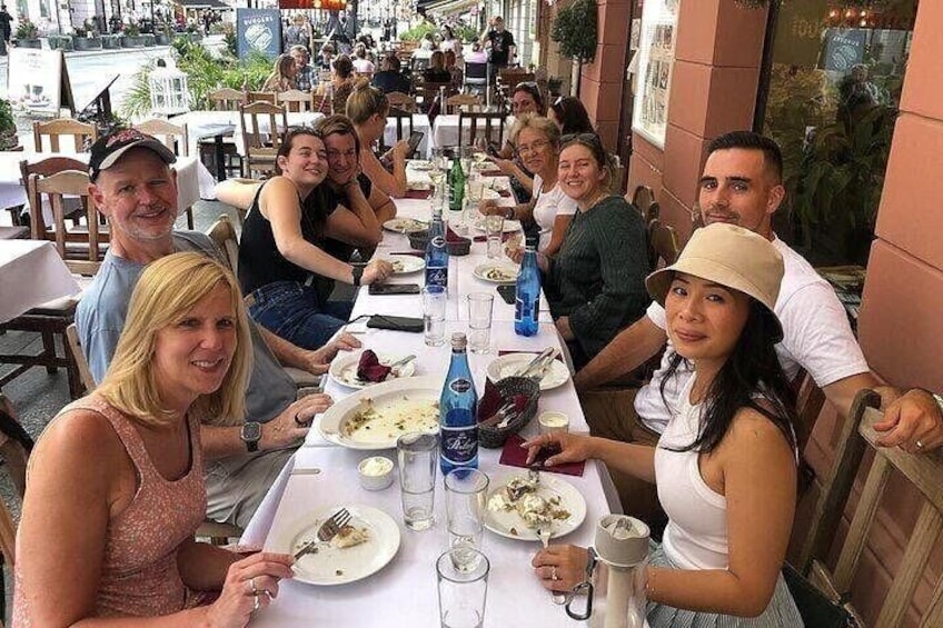 A group of people dining at an outdoor restaurant with tables and chairs. 1