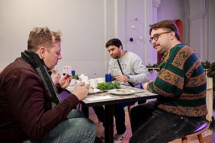 Three people sitting at a table with food and drinks. 4