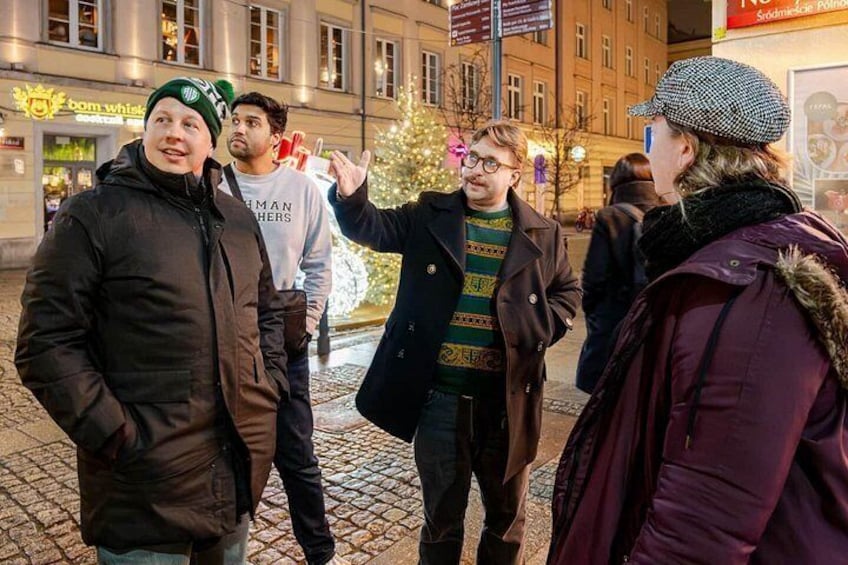 A group of people standing on a cobblestone street at night. 3