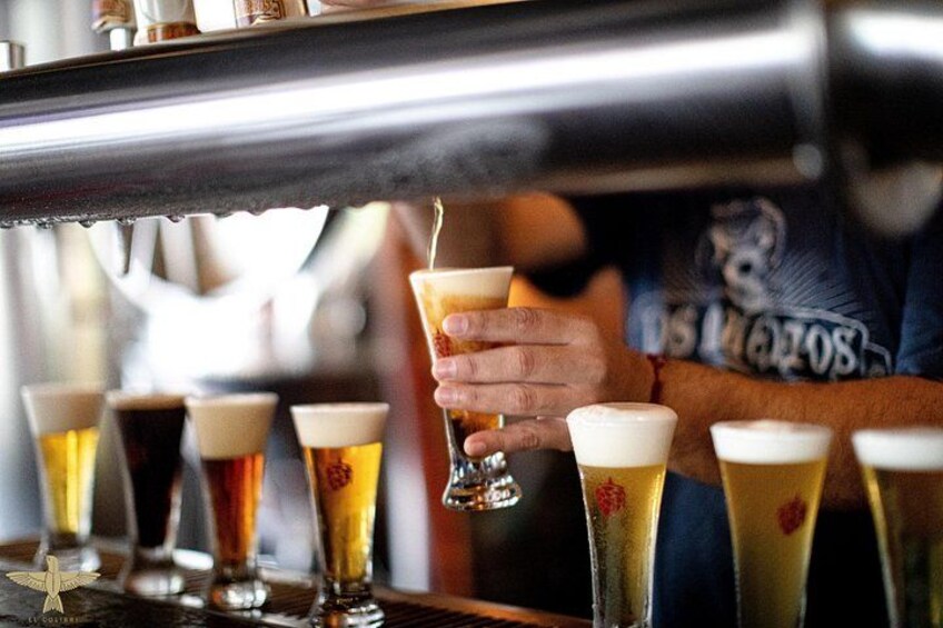 A person pouring a drink into a glass, with several other glasses of beer in the background. 3