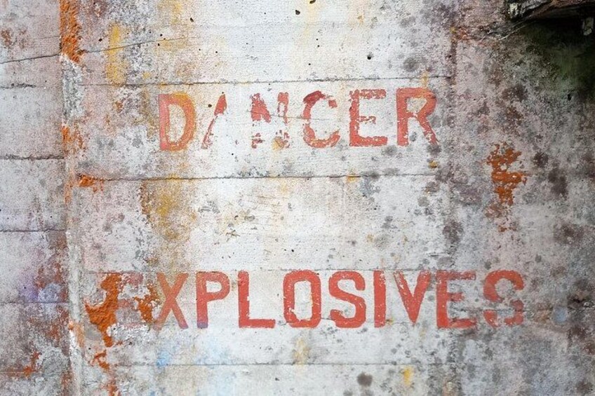 A wall with the words 'DANGER EXPLOSIVES' written in red letters. 1
