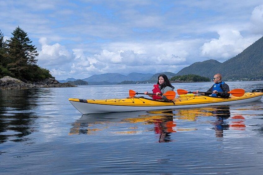 Two people kayaking on a calm lake with mountains in the background. 4