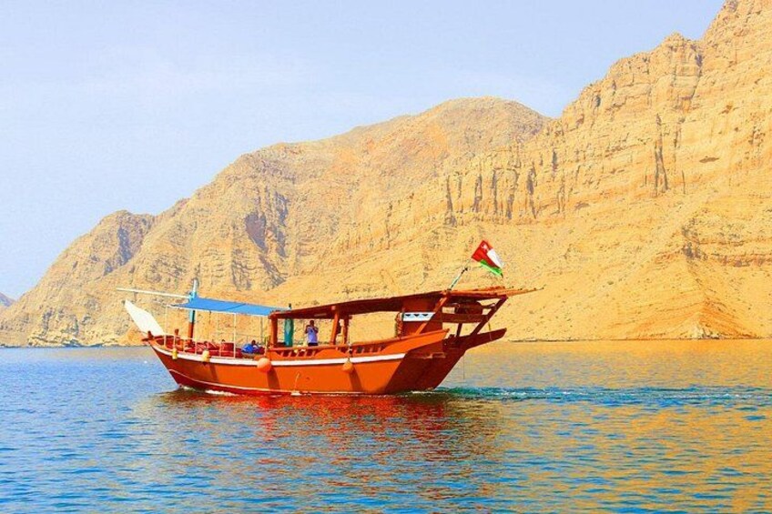 A boat with a flag on a calm body of water with a mountainous backdrop. 3