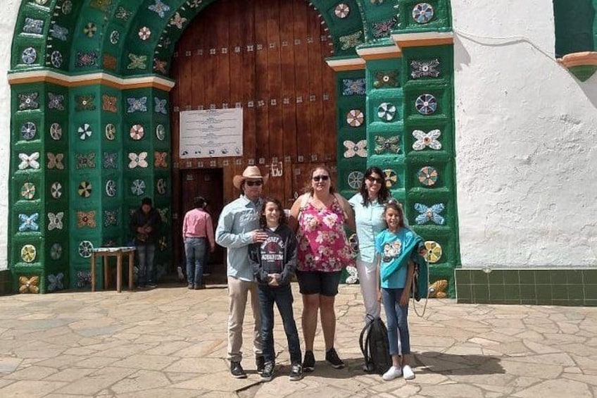 Una familia frente a un edificio con fachada verde y puerta de madera. 1