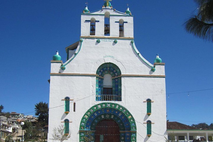 Una iglesia blanca con detalles verdes y una torre de reloj. 3