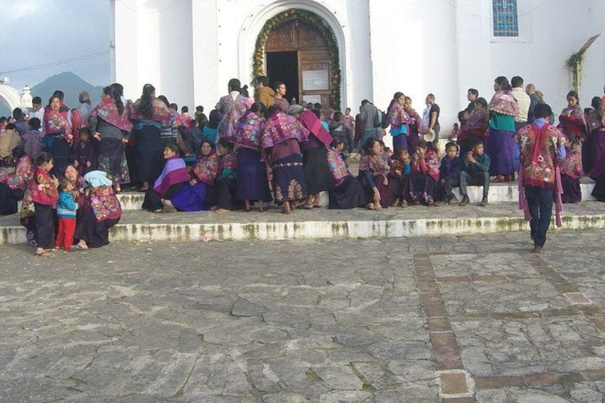 Un grupo de personas reunidas frente a un edificio blanco con un gran arco de entrada. 5