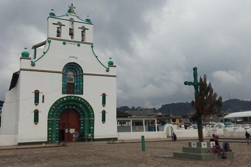 Una iglesia blanca con detalles en verde y un amplio arco de entrada. 2