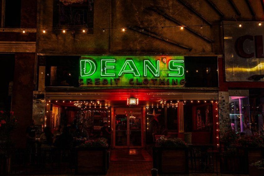 Een etalage met een neonbord waarop staat 'DEANS CREDIT CLOTHING'. 2