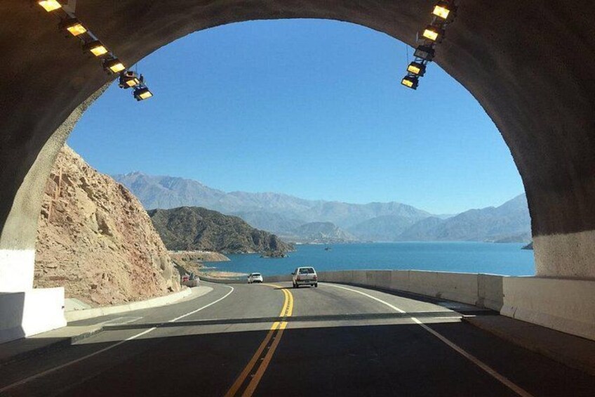 Un túnel de autopista con vistas a montañas y un lago. 1