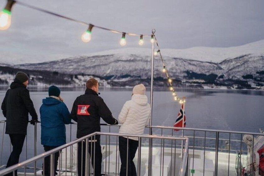 En gruppe mennesker på en båd, et snøklædt landskab og et flag. 3