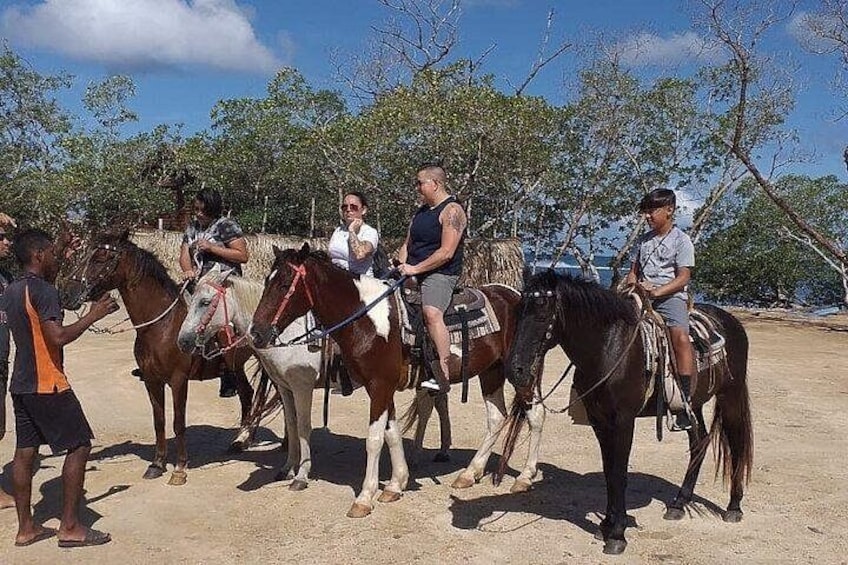 A group of people on horseback in an outdoor setting with trees and a clear sky. 5