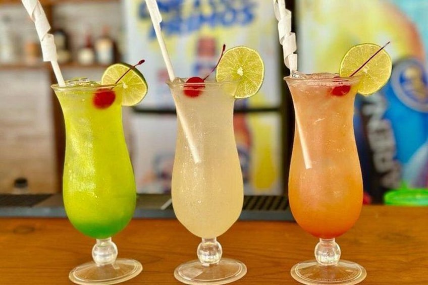 Three colorful cocktails with straws and garnishes on a bar counter. 4
