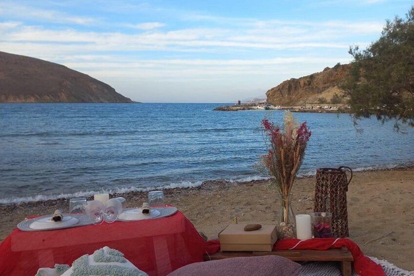A beach with a table set for a meal, overlooking the sea. 3
