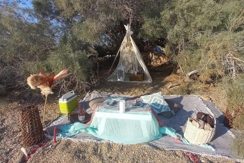 A picnic setup with a table, a basket, and a teepee in a natural setting. 3