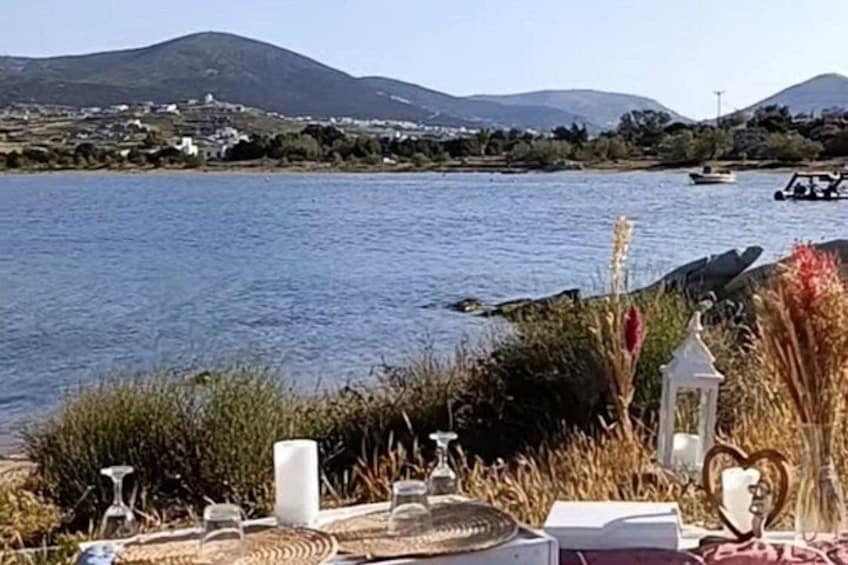 A lakeside table set with glasses, candles, and a heart-shaped decoration. 2