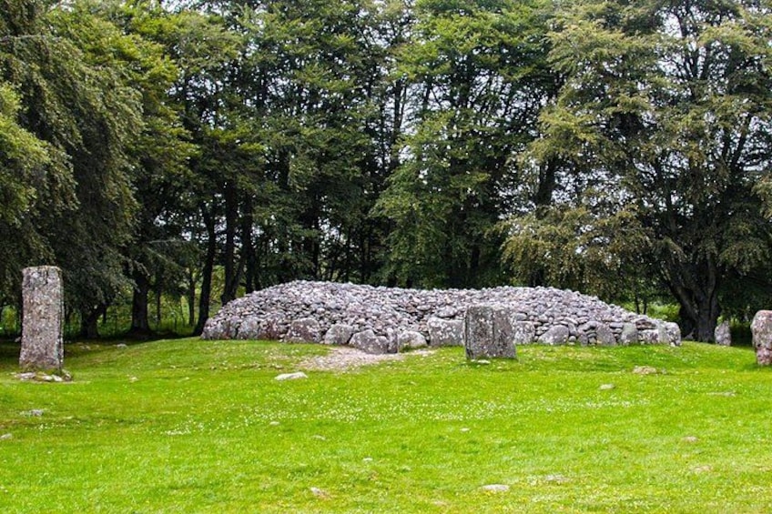 Un círculo de piedras rodeado de árboles en un área cubierta de hierba. 5