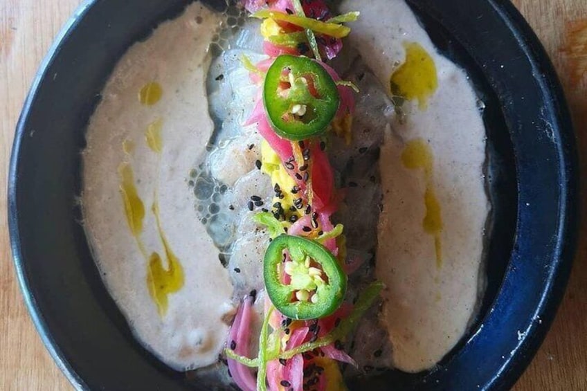 A dish with a creamy sauce, sliced jalapeños, and shredded carrots. 3