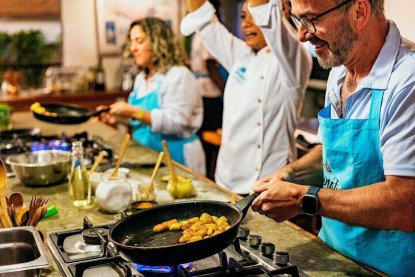 A kitchen with chefs frying food in pans, cooking utensils, and a gas stove. 1