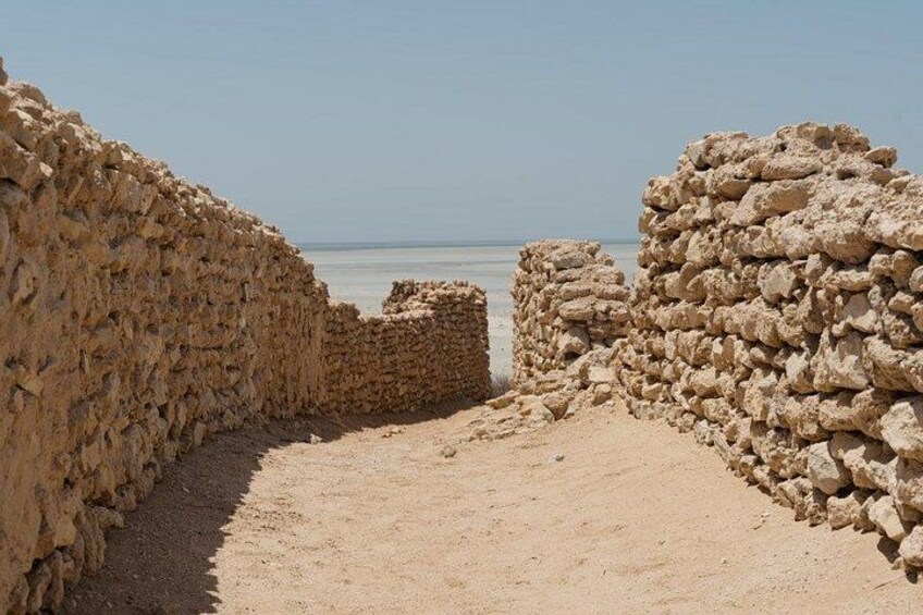 A stone wall leading to a beach with the ocean in the background. 4