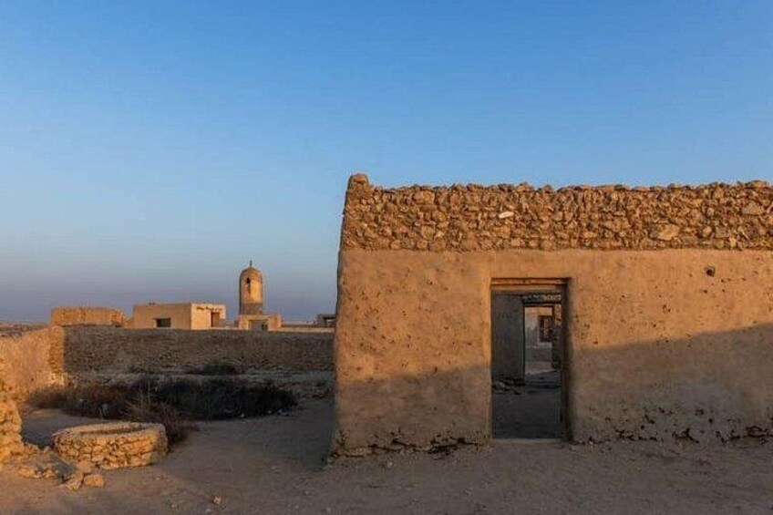 A desert landscape with a stone building and a distant tower. 2