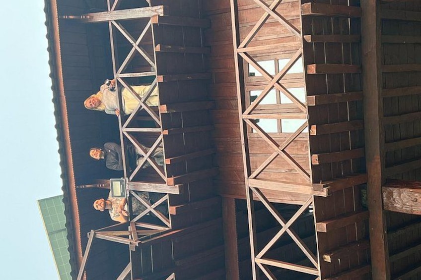 Een houten constructie met een ladder en een persoon zittend aan een tafel. 5