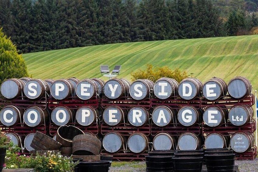 A sign with barrels and the text 'SPEYSIDE COOPERAGE Ltd' against a backdrop of a green field and trees. 2