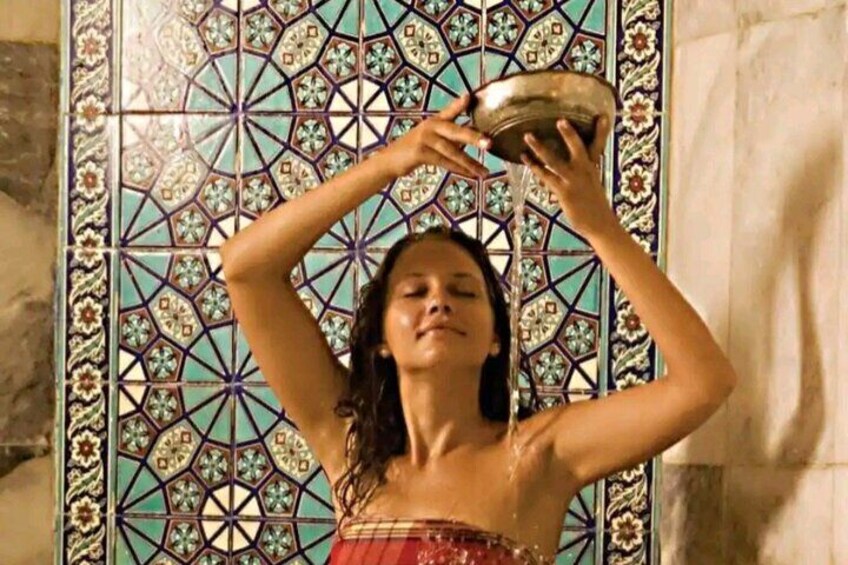 A person holding a bowl above their head in front of a tiled wall. 1
