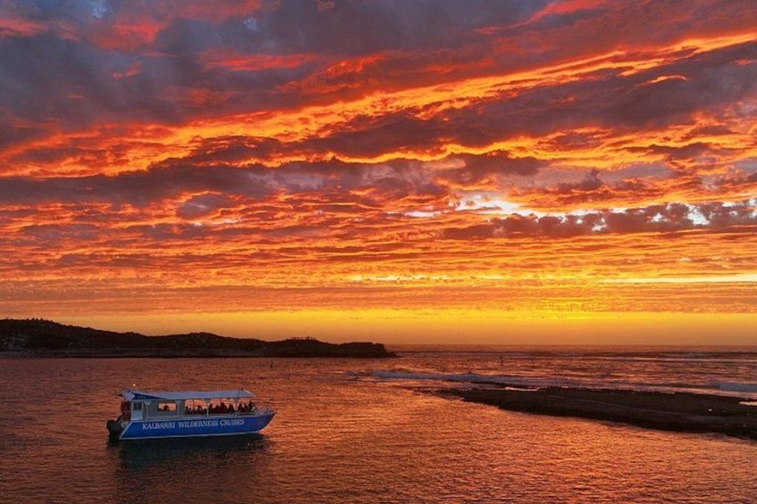 A sunset over a body of water with a boat named 'Kalamata Island Cruises.' 1