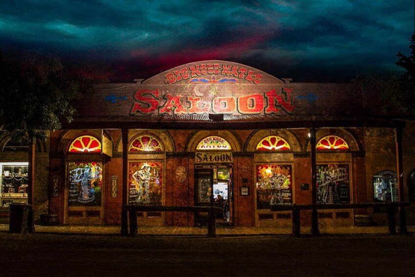 Un bâtiment orné d’une enseigne au néon sur laquelle on peut lire « Big Noise Saloon » et doté de fenêtres en arc de cercle. 5
