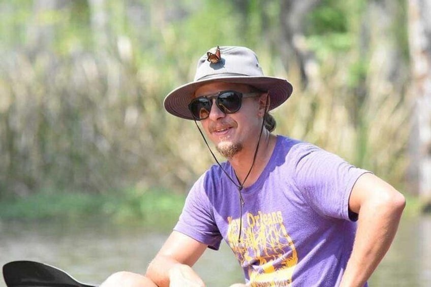 A person in a purple shirt and hat, holding a paddle, on a calm body of water. 2