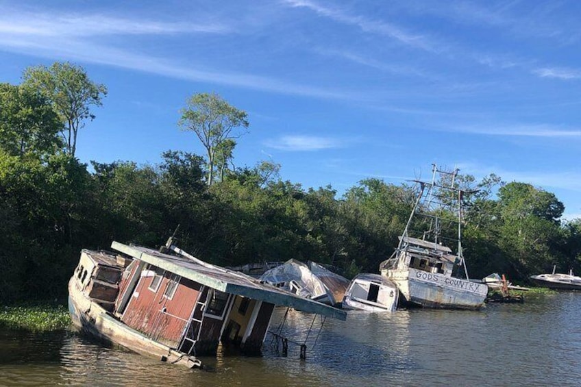 A river with several boats, including a houseboat named 'GODS COMVRY,' partially submerged and tilted. 3