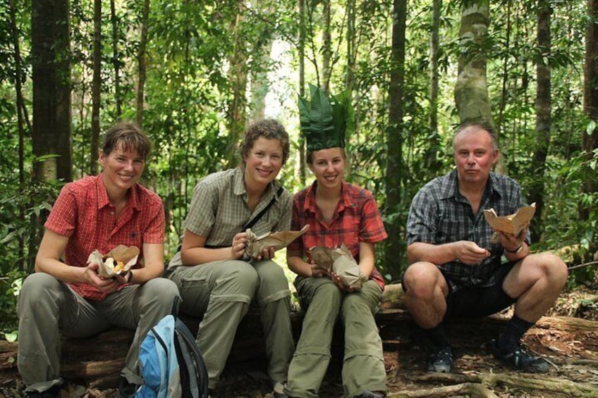 Four people sitting on a log in a forest, holding food packages. 1