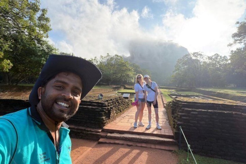 A person taking a selfie with two tourists standing on a pathway in a historical site. 2