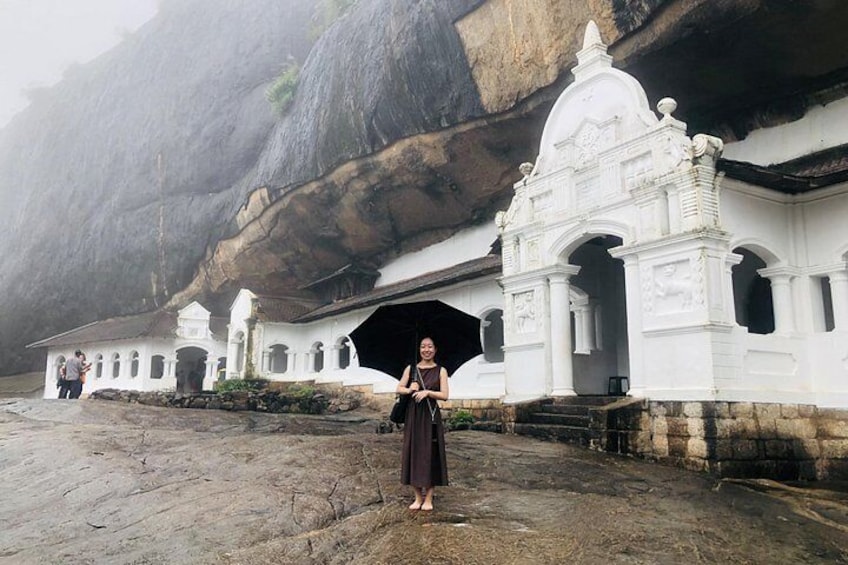 Une personne se tient devant un temple blanc, avec une grande formation rocheuse en arrière-plan. 4
