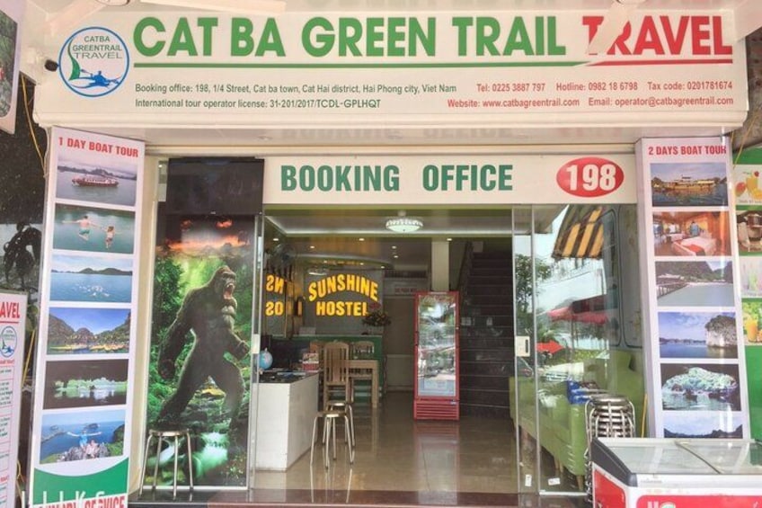 A booking office for Cat Ba Green Trail Travel with a 1-day and 2-day boat tour sign. 4