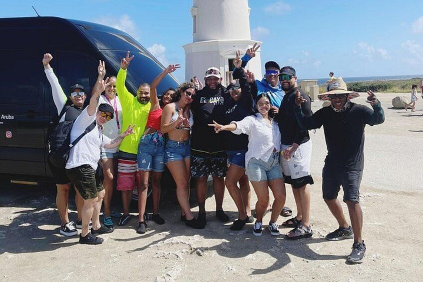 A group of people posing in front of a helicopter and a lighthouse. 3