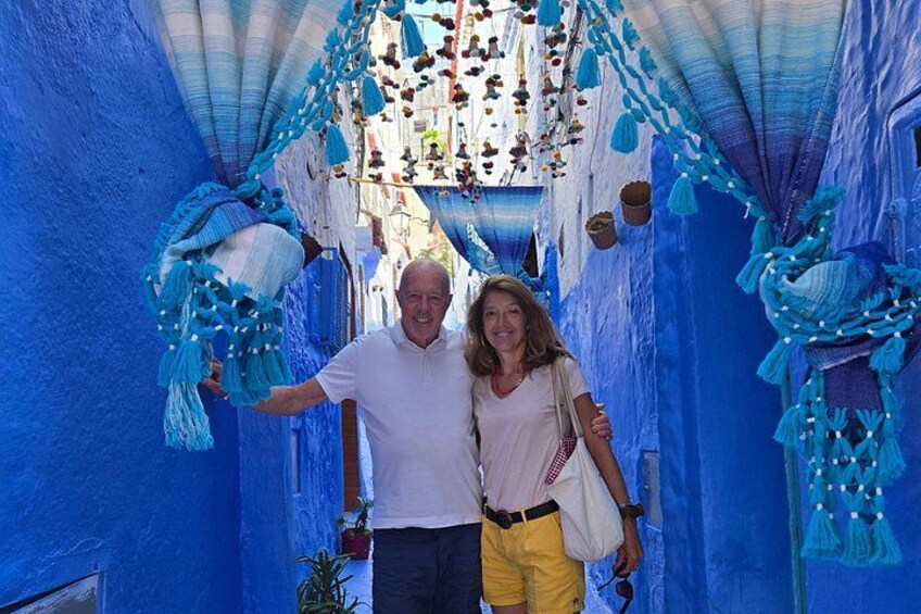 Een smalle steeg met blauwe muren en hangende decoraties. 2