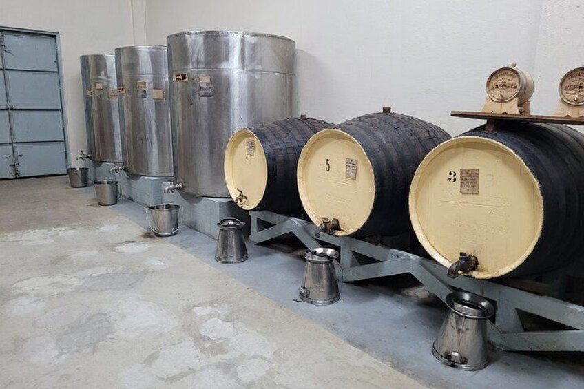 Stainless steel fermentation tanks and wooden barrels in a storage area. 5
