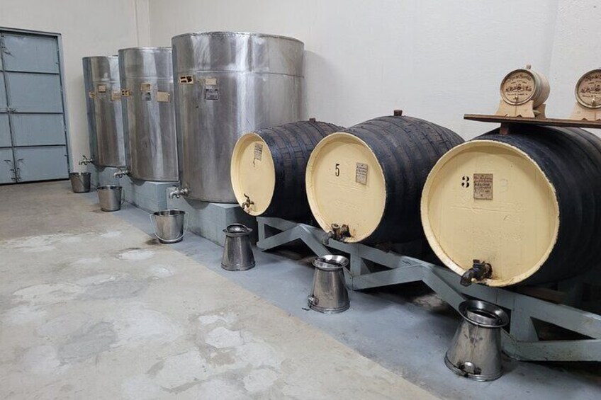 Stainless steel fermentation tanks and wooden barrels in a storage facility. 4