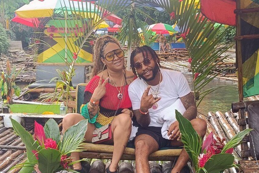 Two people sitting on a boat surrounded by tropical plants and colorful umbrellas. 2