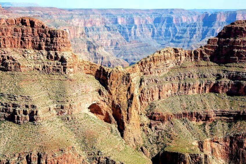A canyon with layered rock formations and sparse vegetation. 5