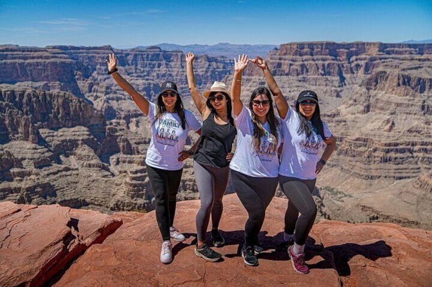 Four people posing on a rock with a canyon in the background. 2