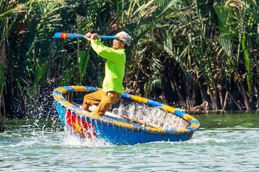 Een persoon roeit in een kleurrijke boot op het water, omringd door weelderige begroeiing. 1