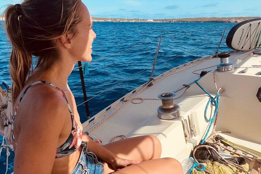 Una persona navegando en un velero, con el mar y una costa lejana al fondo. 5
