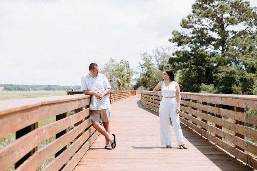 A wooden bridge with railings, surrounded by greenery and trees. 5