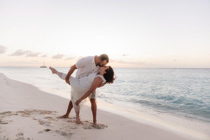A couple embracing on a beach with a boat in the background. 3