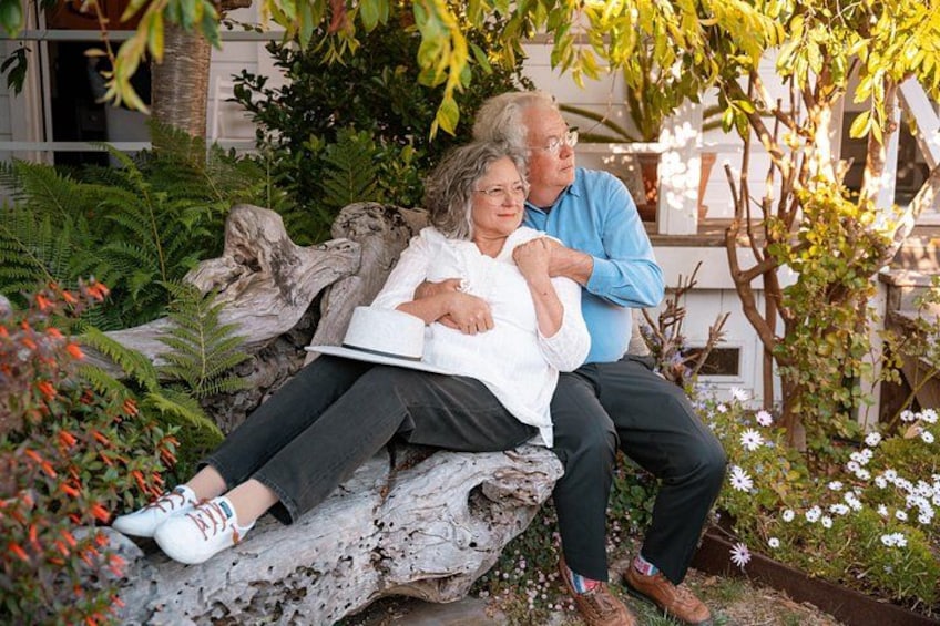 Two people sitting on a rock with a garden in the background. 4