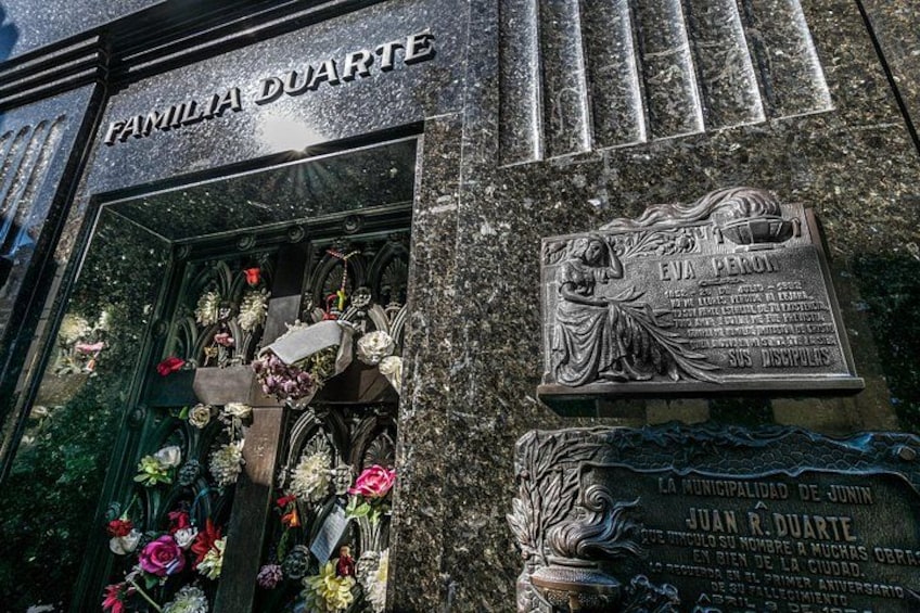 A storefront with a plaque and flowers. 2