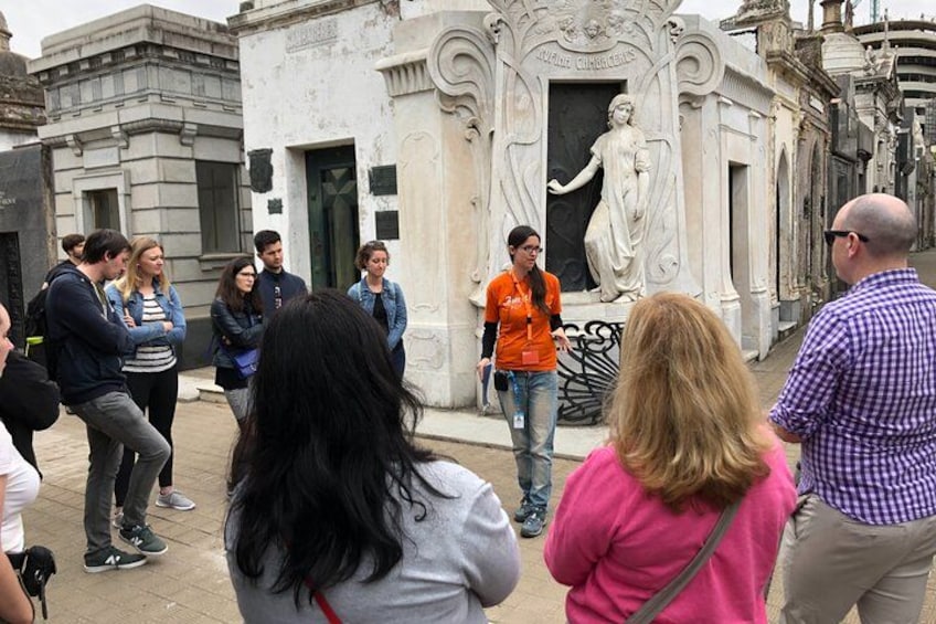 Un groupe de personnes s’est rassemblé autour d’une statue, dans un espace extérieur agrémenté d’une architecture de style classique. 2