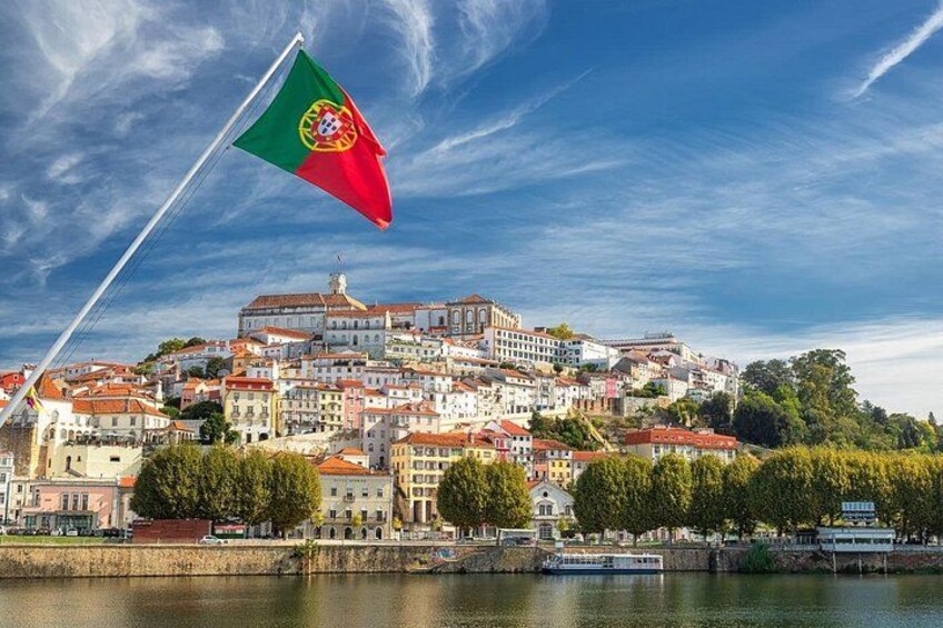 A coastal town with a prominent flag, buildings with red roofs, and a body of water. 1